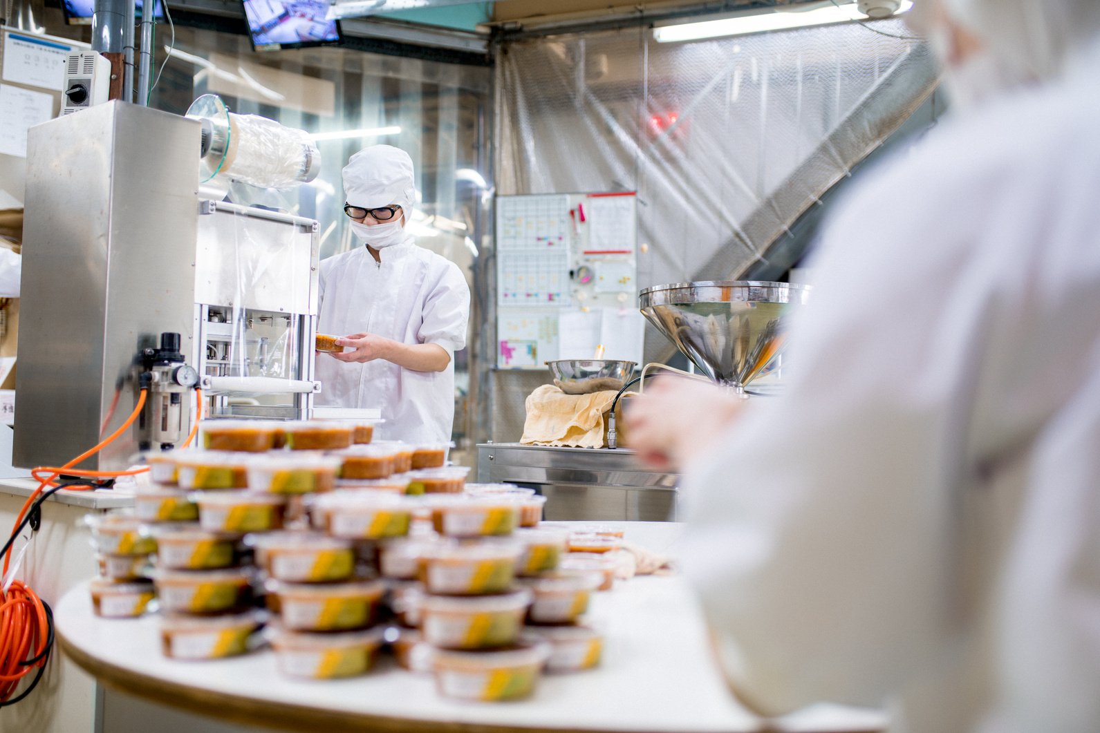 a group of food factory production operatives working on a factory line, packaging products.