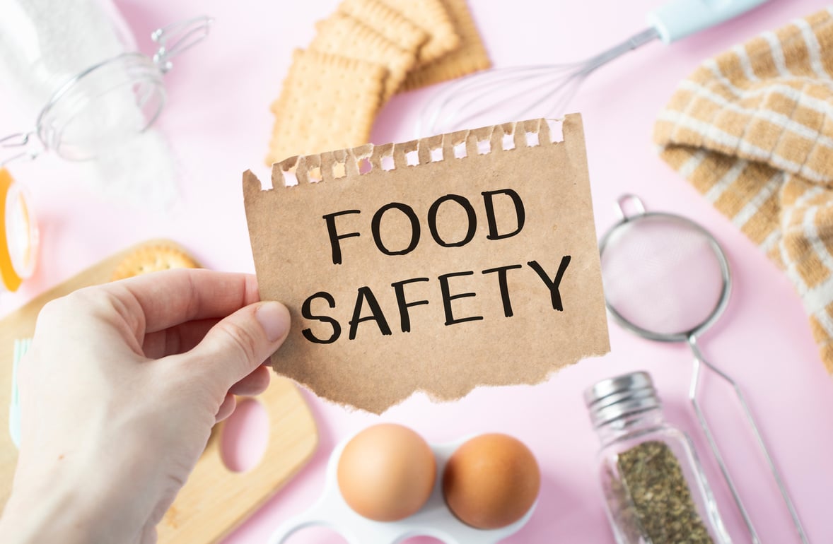 Food safety concept with hand holding a piece of paper with the word food safety written on it.