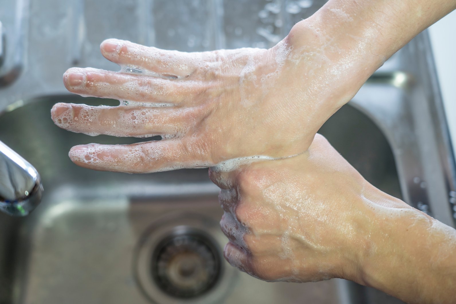 a worker washing their hands in a sink