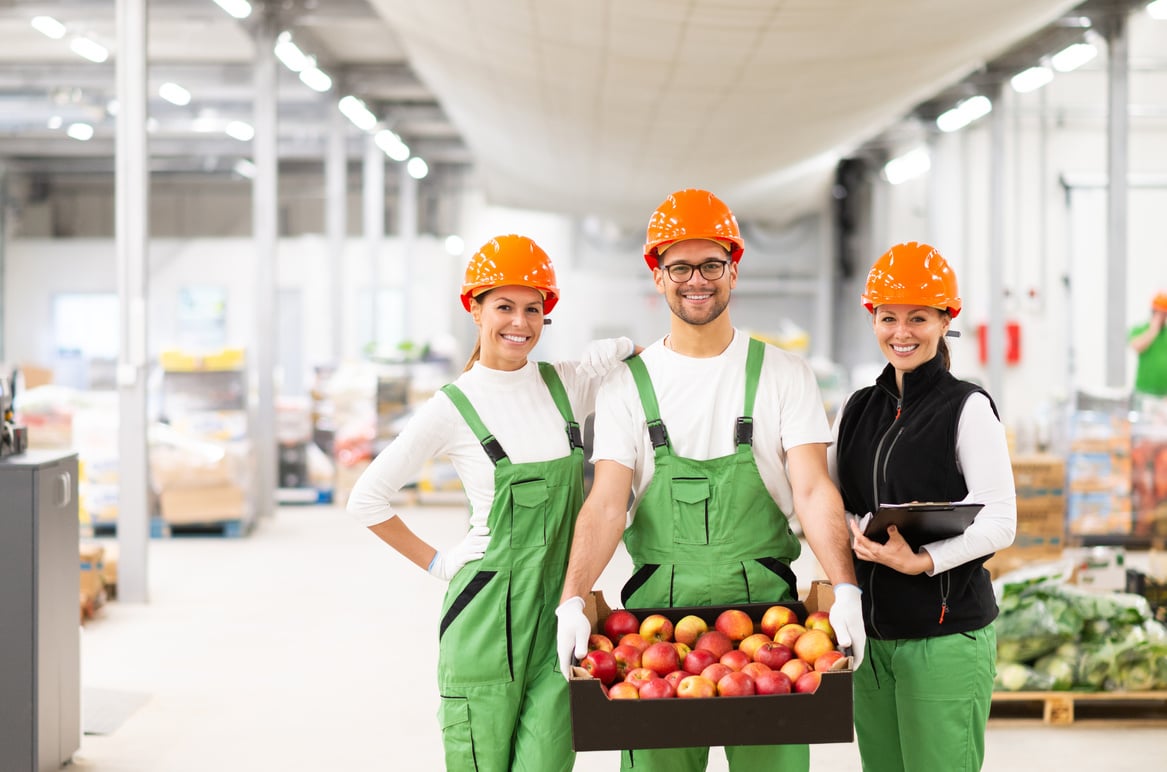 three people in hard hats and overalls standing in a warehouse