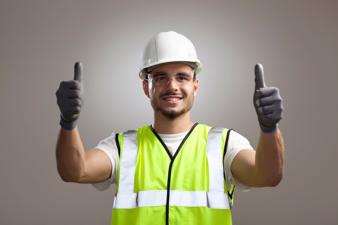 a person in a hard hat and safety vest giving the thumbs up