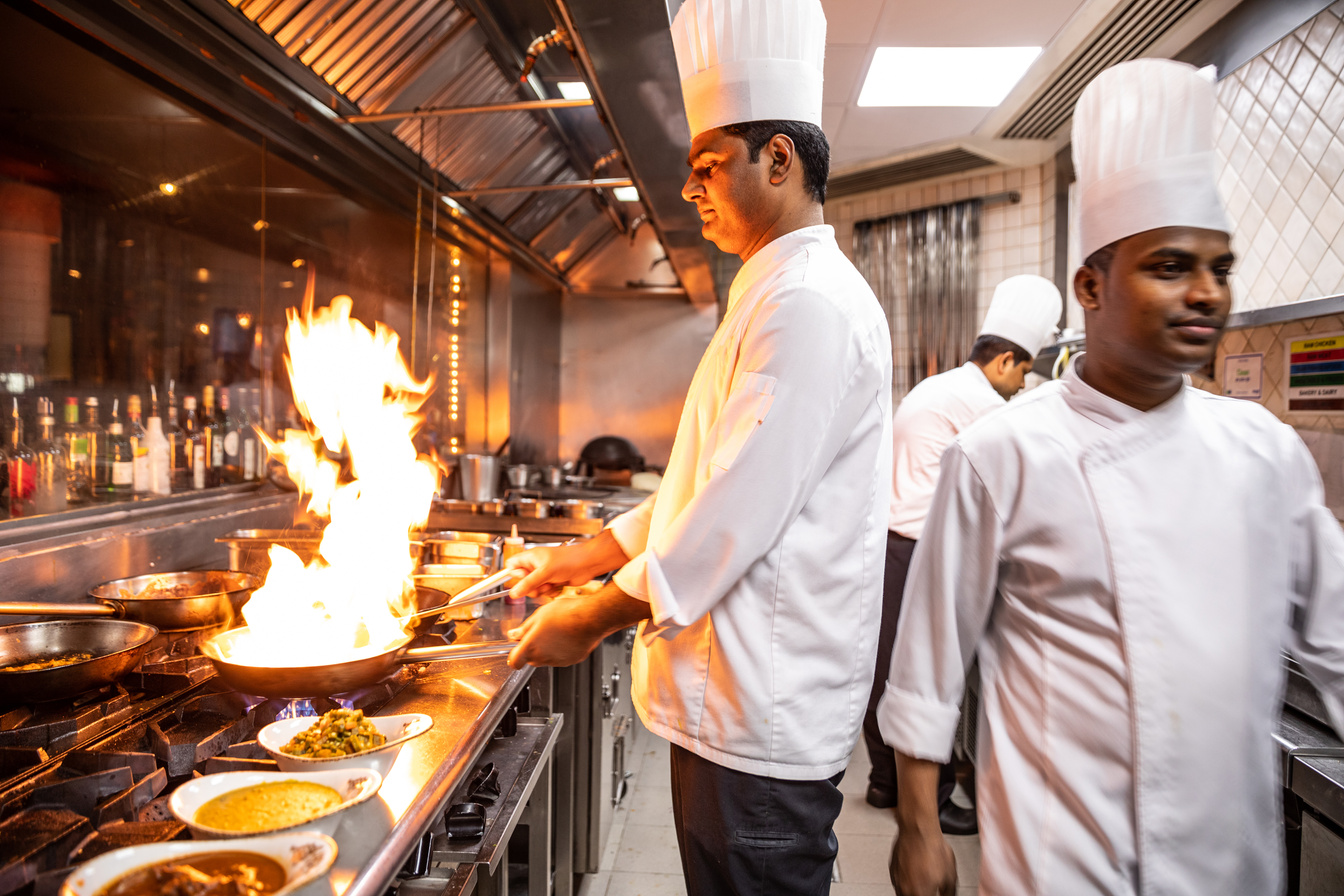 Chefs preparing food in a commercial restaurant Indian kitchen wearing all the PPE and taking all health & safety Precautions.